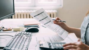 Person reviewing billing documents and using a calculator at a desk.
